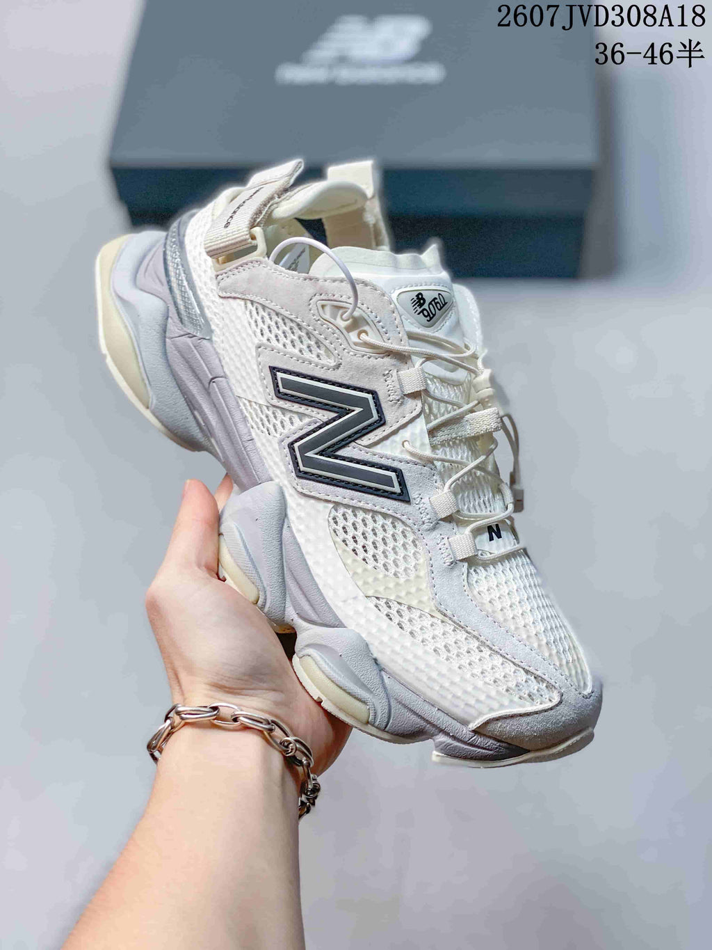 Angled side view of a white and light gray New Balance 9060 sneaker showing the mesh upper, layered overlays, and segmented sole.