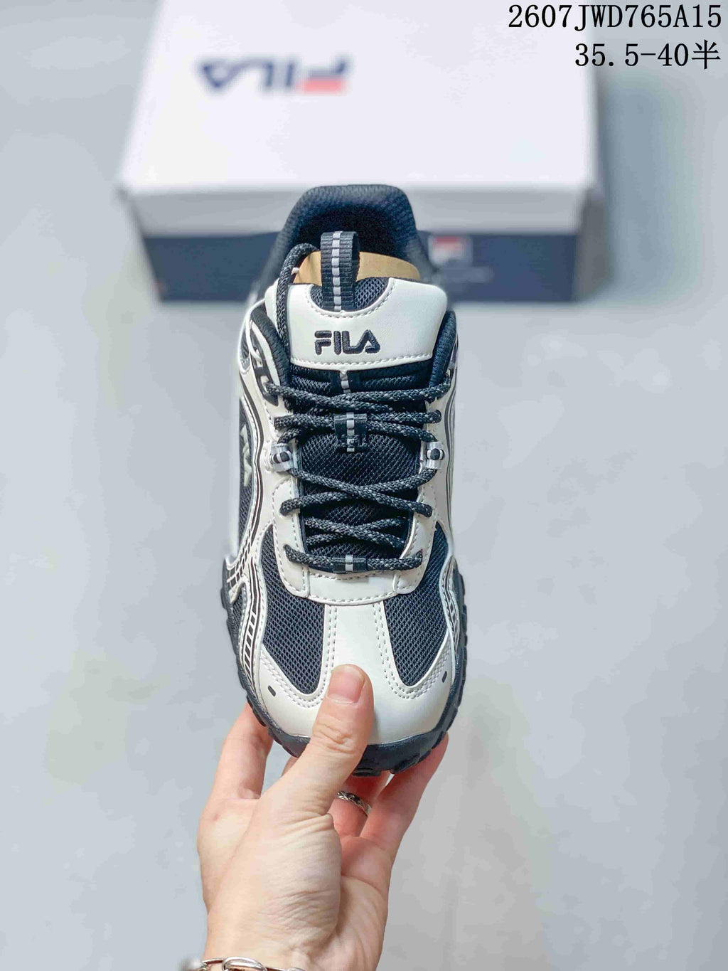 Top view of a black-and-white FILA sneaker showing the lace-up front, padded tongue, and mesh upper; overlay shows style code 2607JWD765A15 and size range 35.5–40.5.