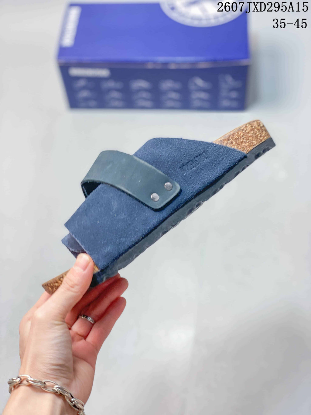 Side view of the navy sandal showing the adjustable strap, layered upper, cork-look midsole, and outsole.