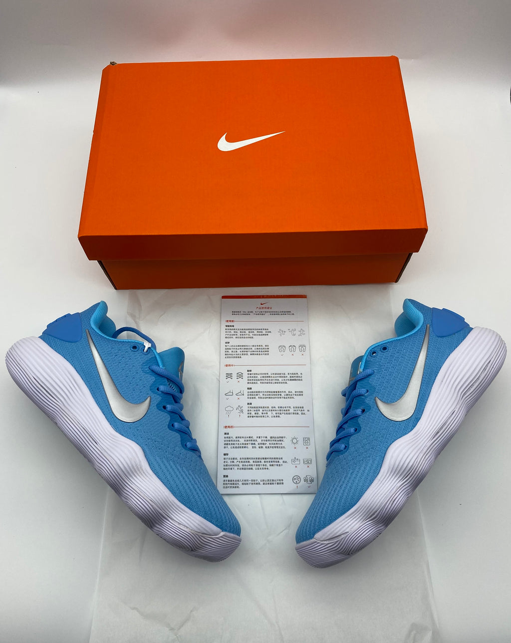 Blue Nike sneakers beside a Nike shoe box and printed card.