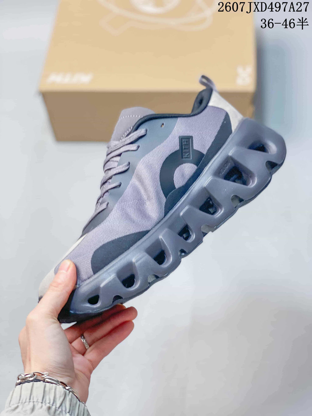 Side view of the gray sneaker showing layered upper panels, On branding and the open-channel sole structure.