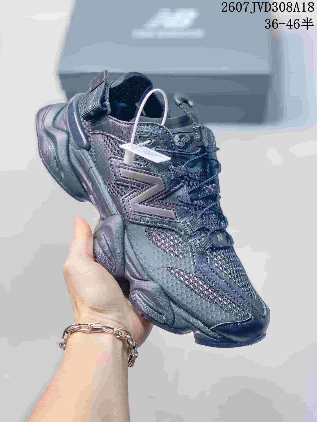 Close-up side view of a dark New Balance 9060 sneaker showing the layered upper, mesh panels, oversized N logo, and sculpted sole.