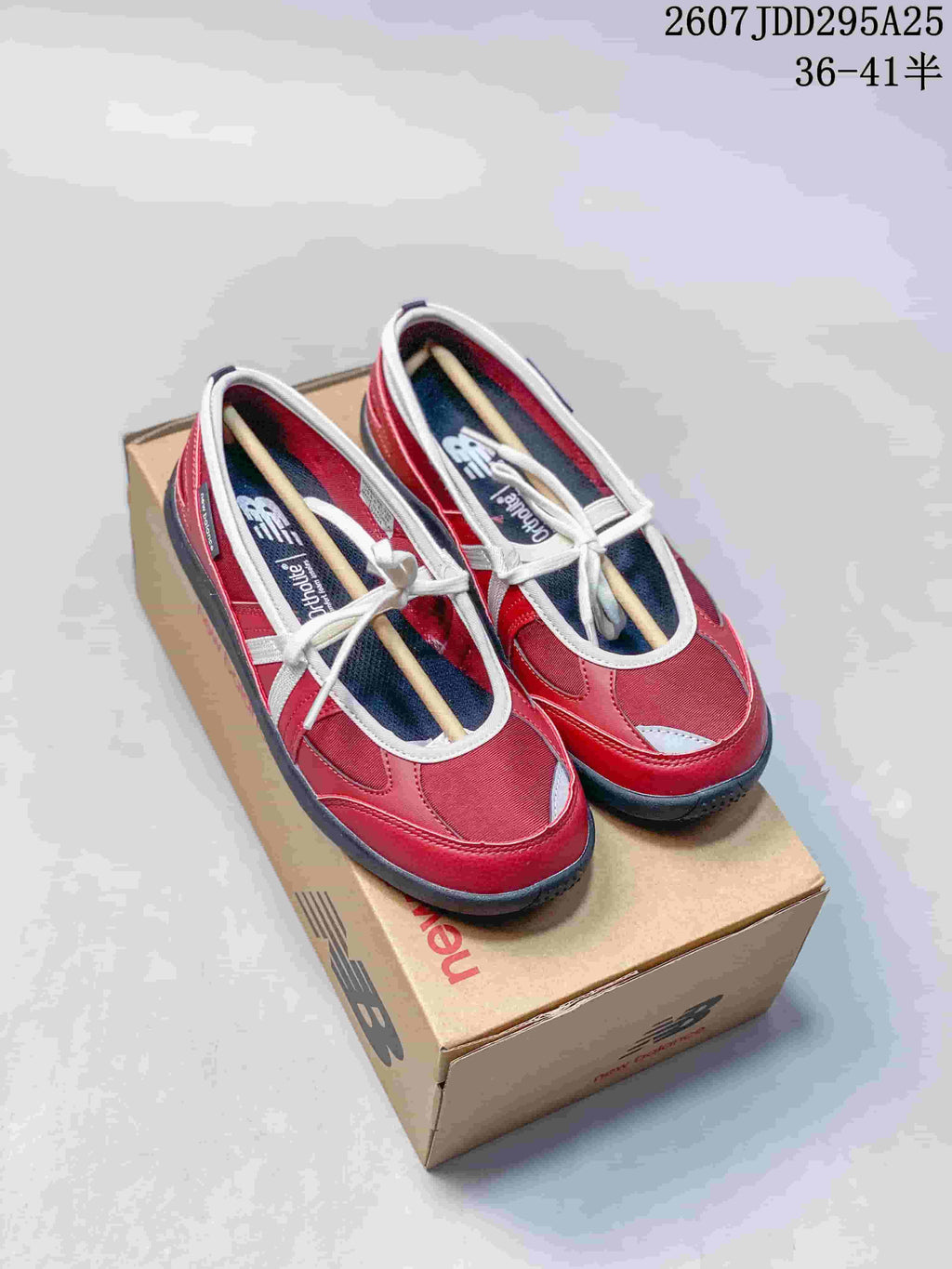 Pair of red New Balance low-top sneakers with white trim displayed on a shoe box.