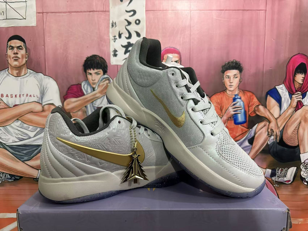 Pair of light gray-white basketball shoes arranged together, showing gold-colored side accents and a decorative charm.