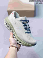 Light gray and pale green On Cloudsurfer 3 sneaker with dark blue laces and a sculpted outsole.