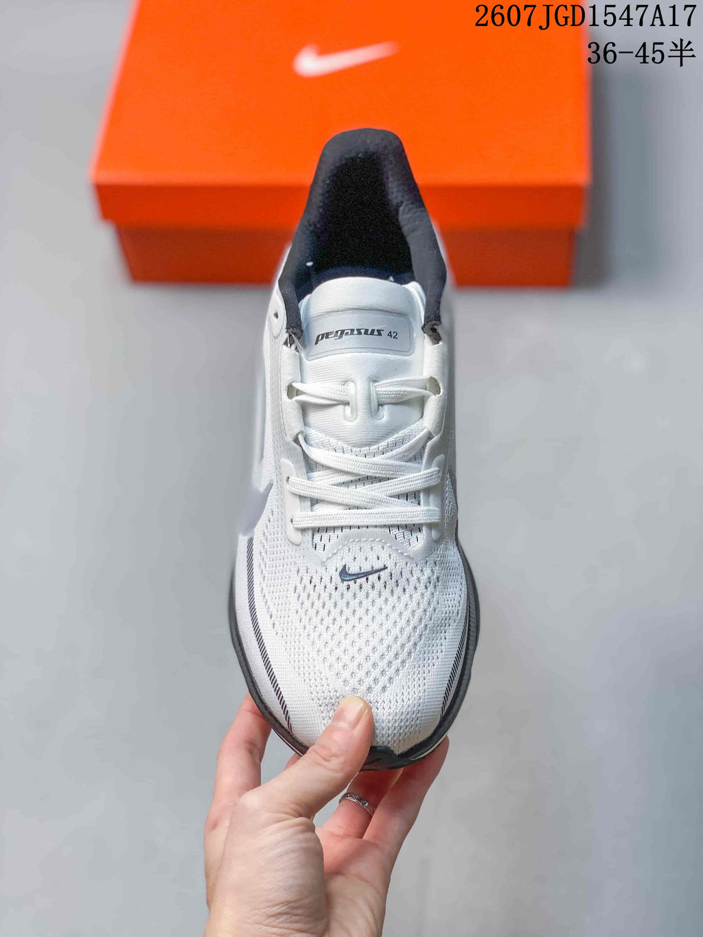 Top view of a white Nike Pegasus 42 shoe showing the laces, tongue branding, perforated toe area, and gray side details.