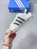 Side profile of the white sneaker showing the black patterned three-stripe panels, shell toe, and textured midsole.