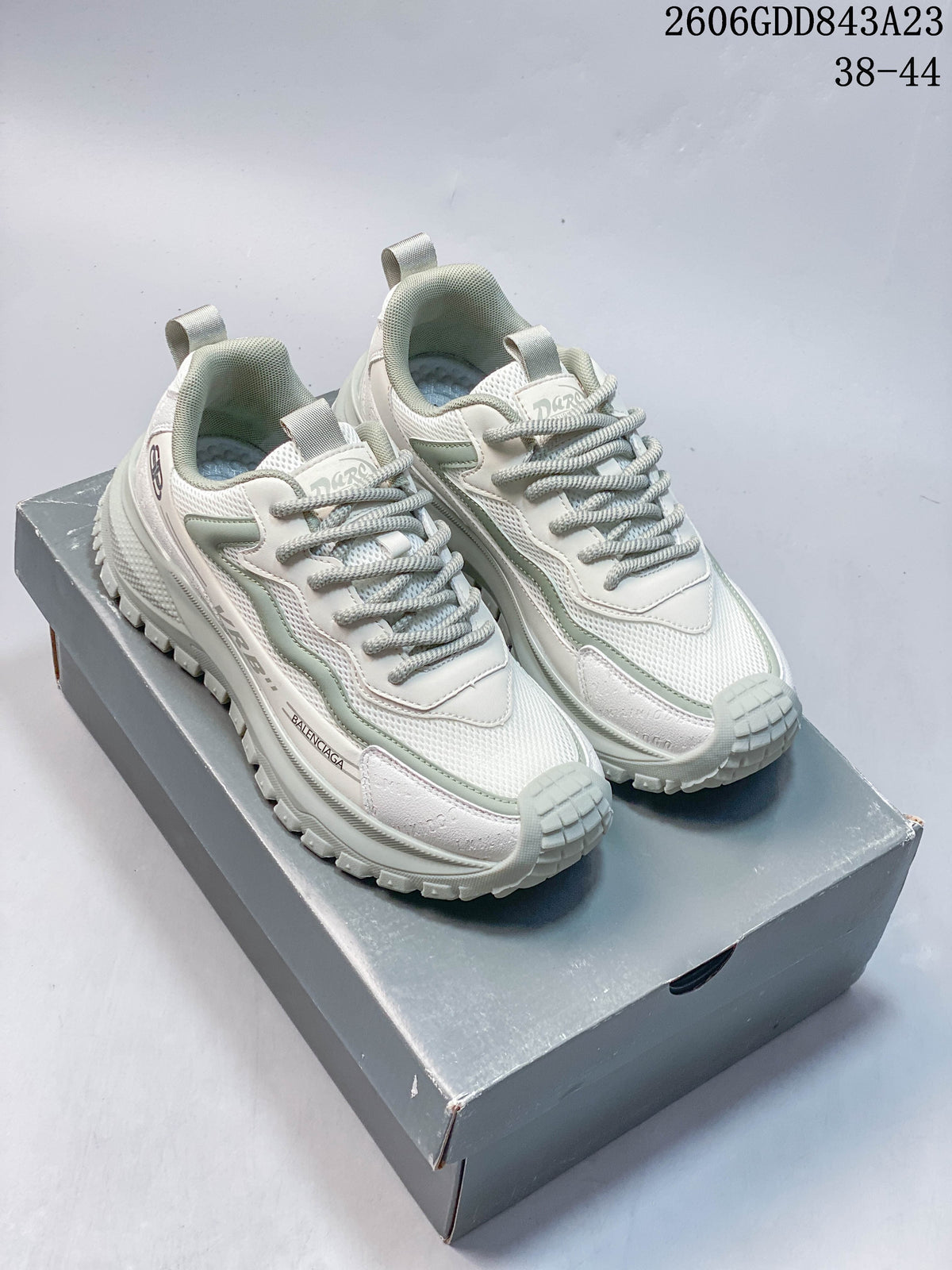 Pair of white and pale sage chunky lace-up sneakers on a gray box; image overlay shows code 2606GDD843A23 and sizes 38–44.