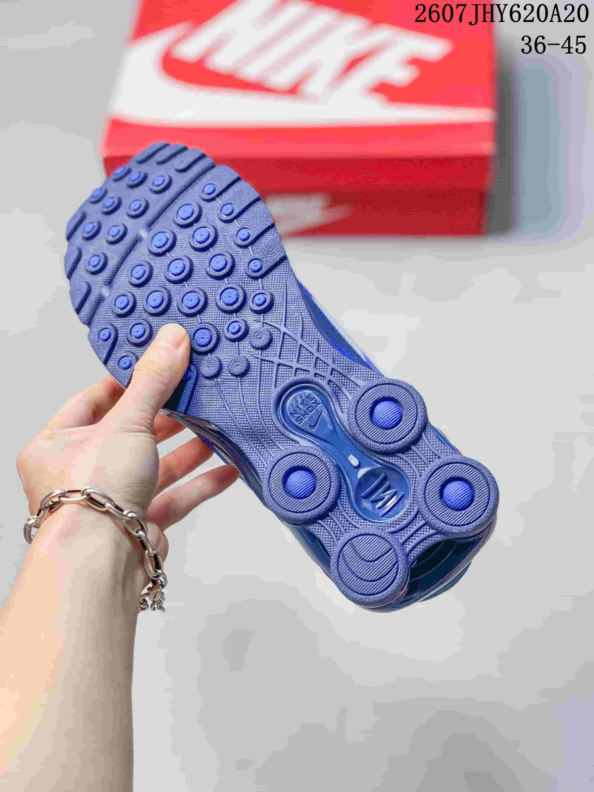 Underside view of the blue sneaker showing the segmented outsole with circular traction elements and cushioning columns.