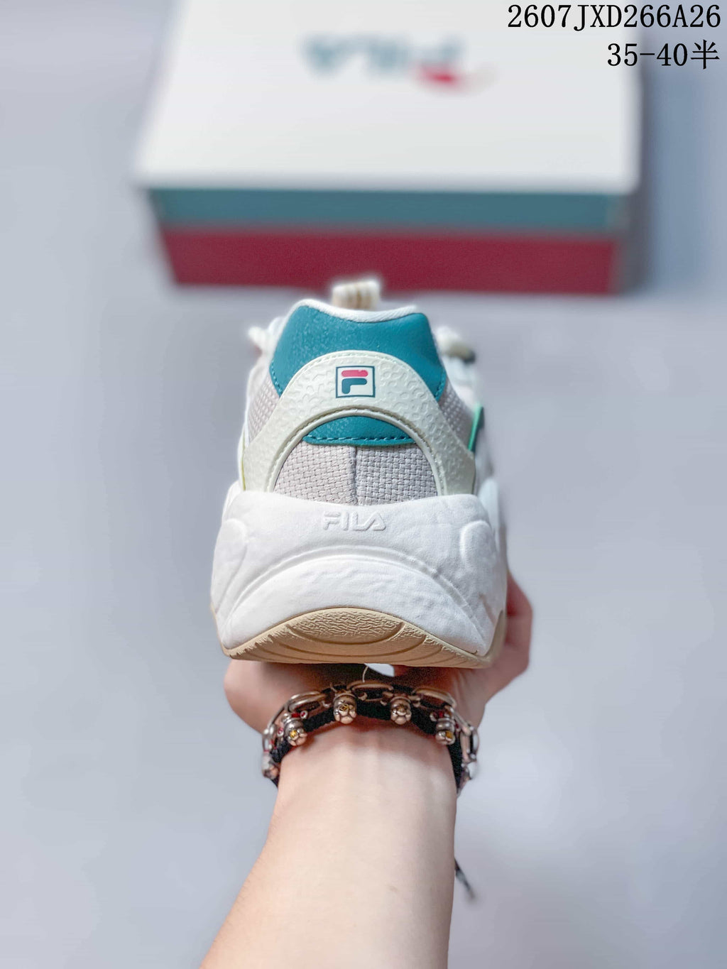 Rear view of a FILA Croissant sneaker showing the teal heel panel, textured upper, and sculpted white sole.