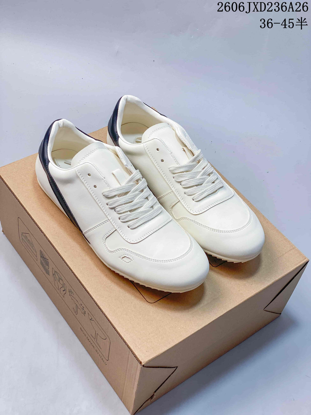 White low-top lace-up sneakers with navy heel accents, photographed on a box.