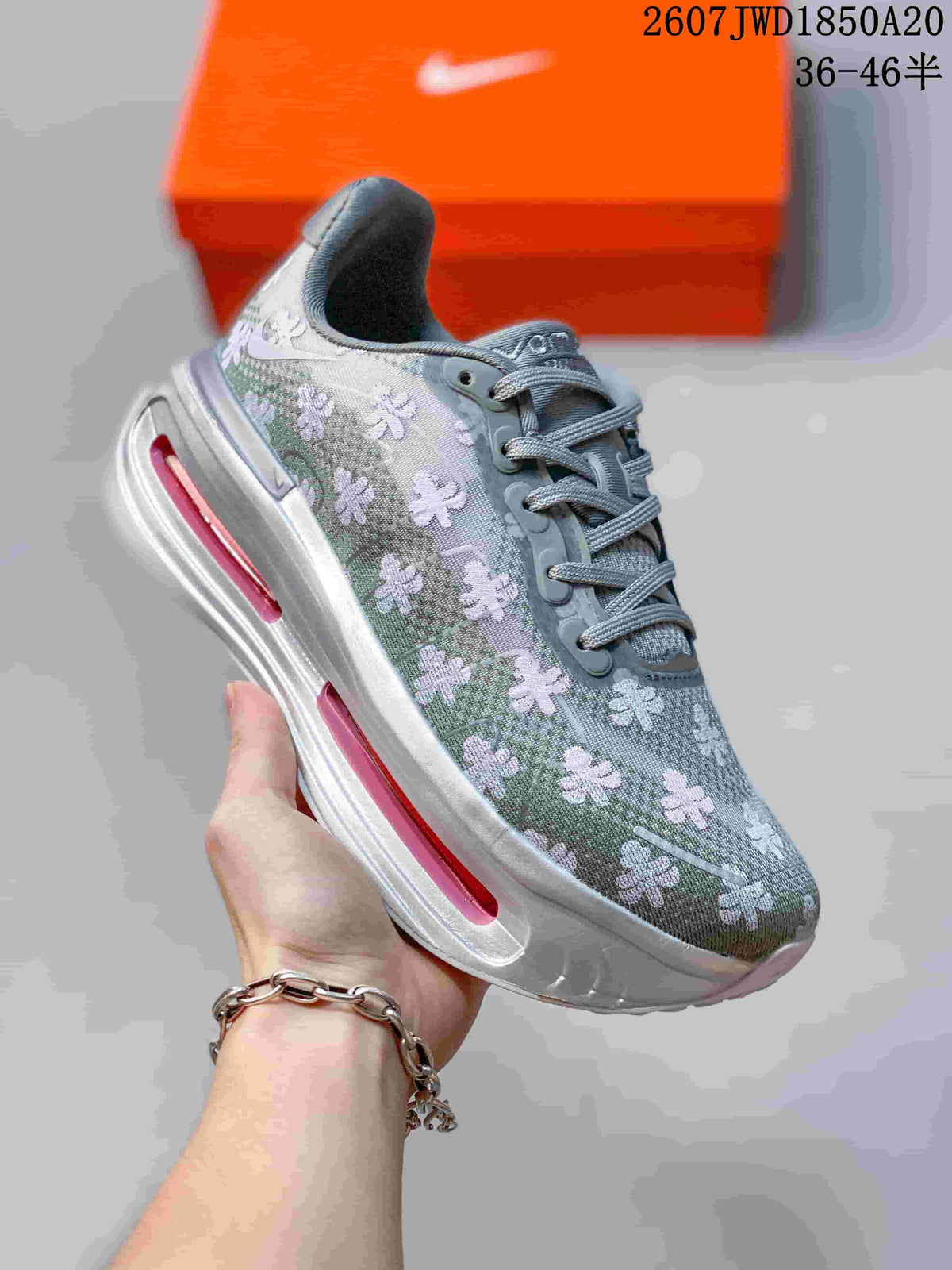 Angled side view of the gray floral sneaker showing the lace system, Nike side branding, and pink midsole windows.