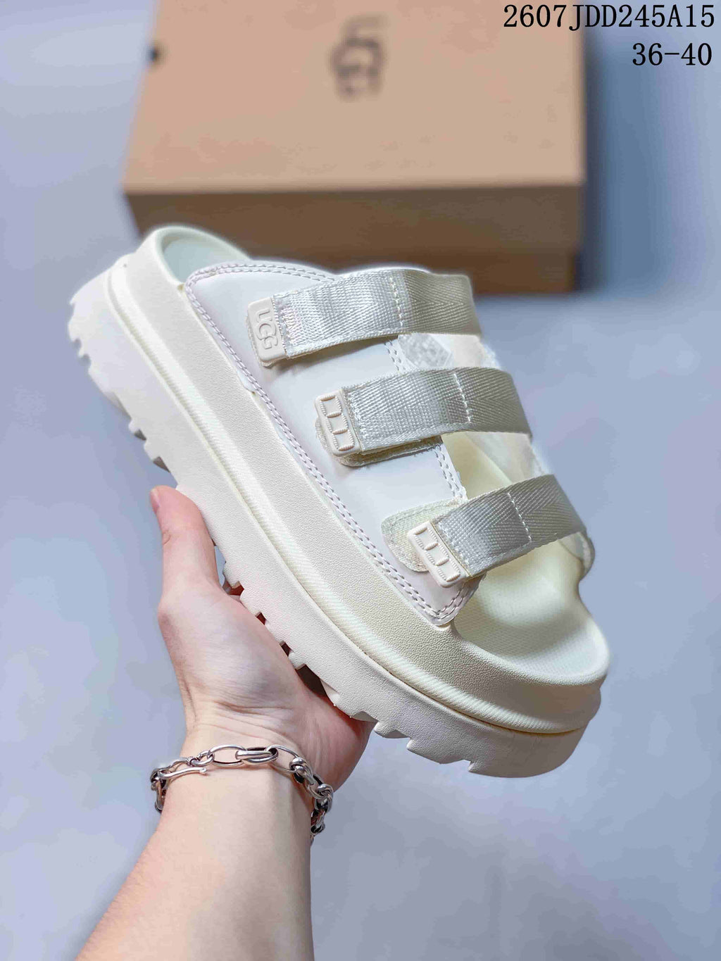 Close-up side view of a white UGG GoldenGlow slide sandal showing the three front straps and thick lugged outsole.