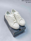 Pair of white Converse One Star J sneakers displayed on a Converse shoebox.