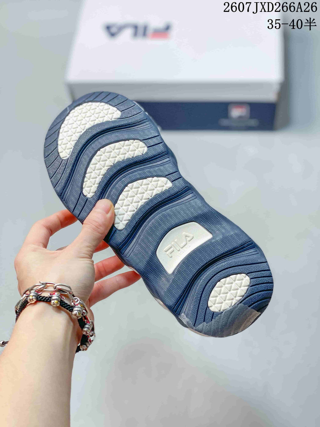 Close-up of the sneaker outsole showing a dark blue tread pattern with contrasting white sections and FILA branding.