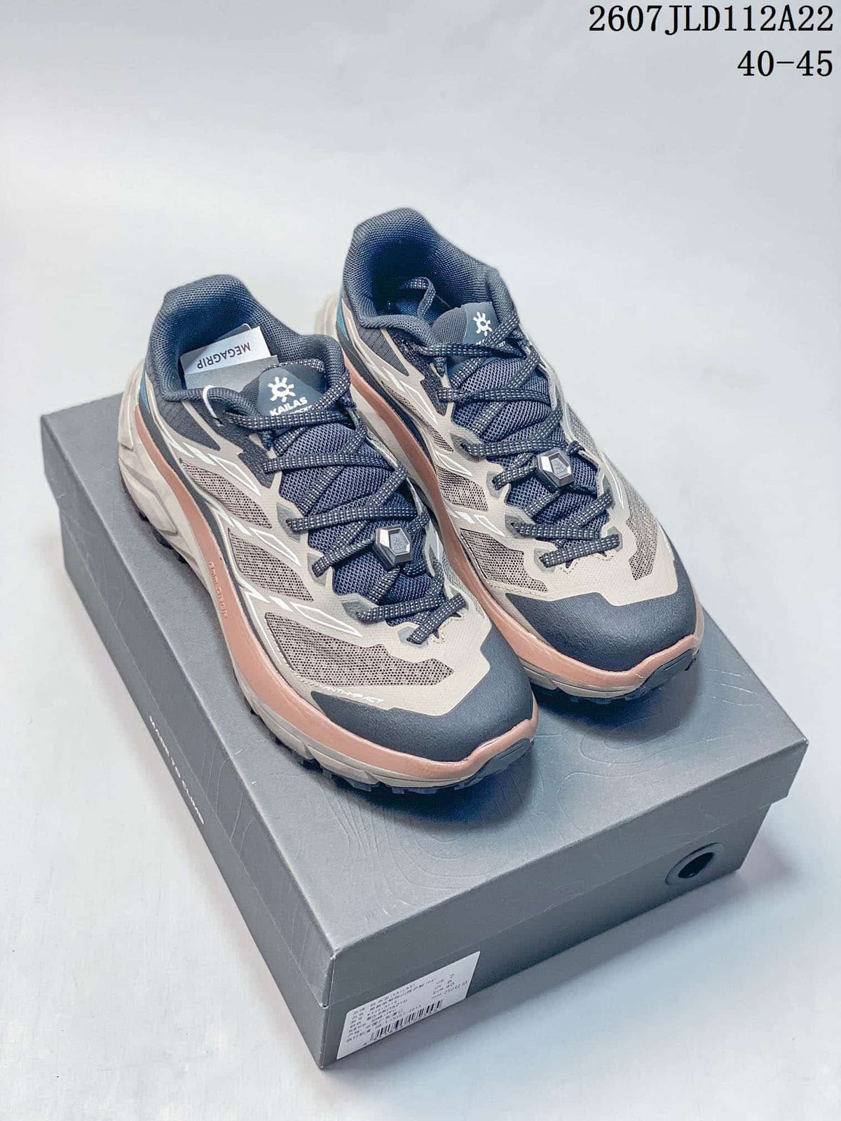 Kailas C4 trail running shoes shown from a front three-quarter angle on a shoebox, with navy and gray mesh uppers, white overlays, and pink midsole accents.