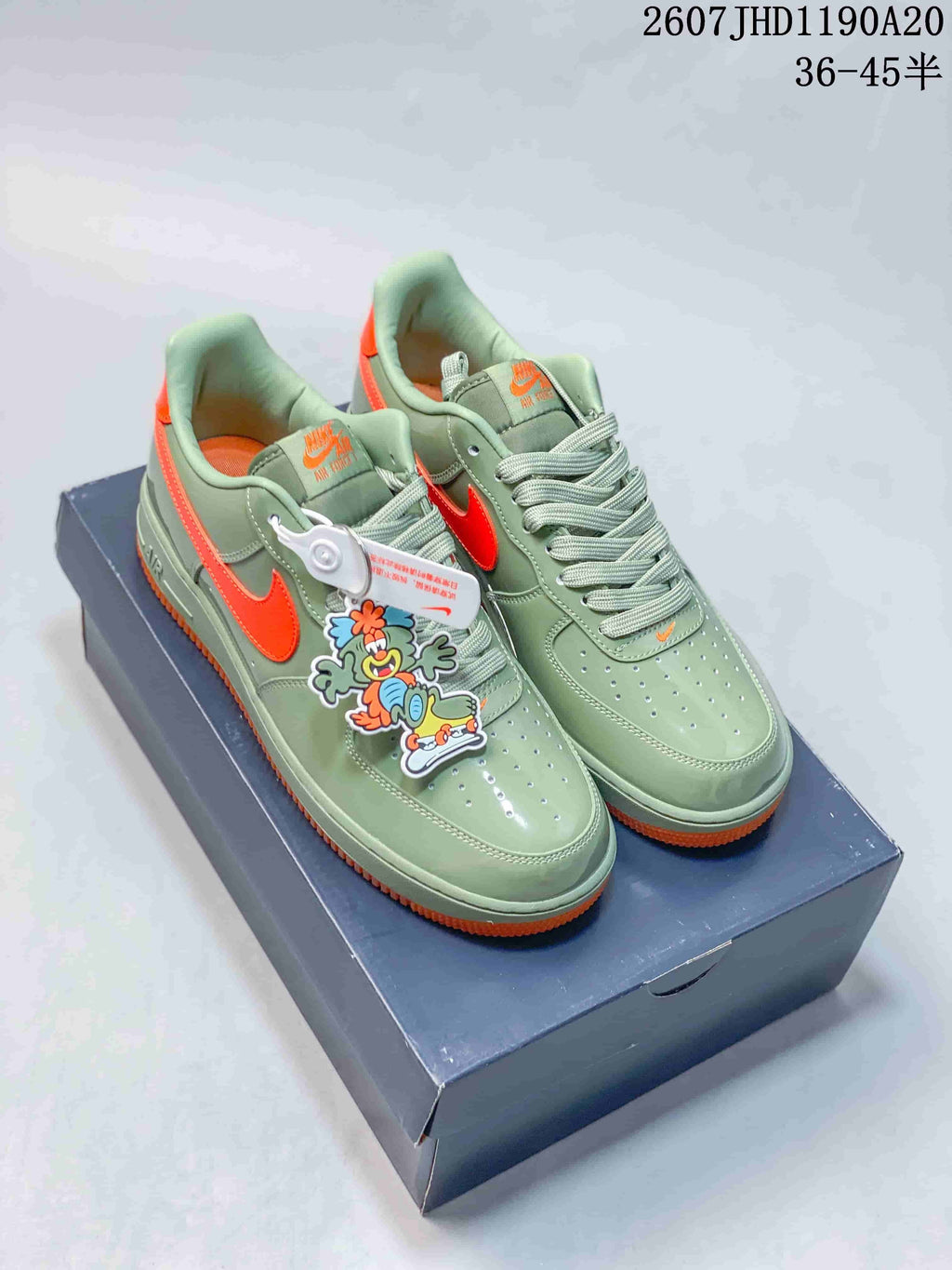 Pair of green and orange low-top sneakers displayed on a shoebox with a decorative cartoon charm.