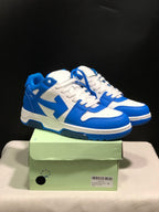 Pair of blue and white low-top sneakers displayed on a green shoebox.