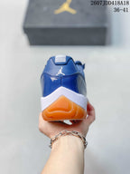 Rear view of the blue high-top sneaker showing the Jordan heel logo, white midsole, and orange outsole.