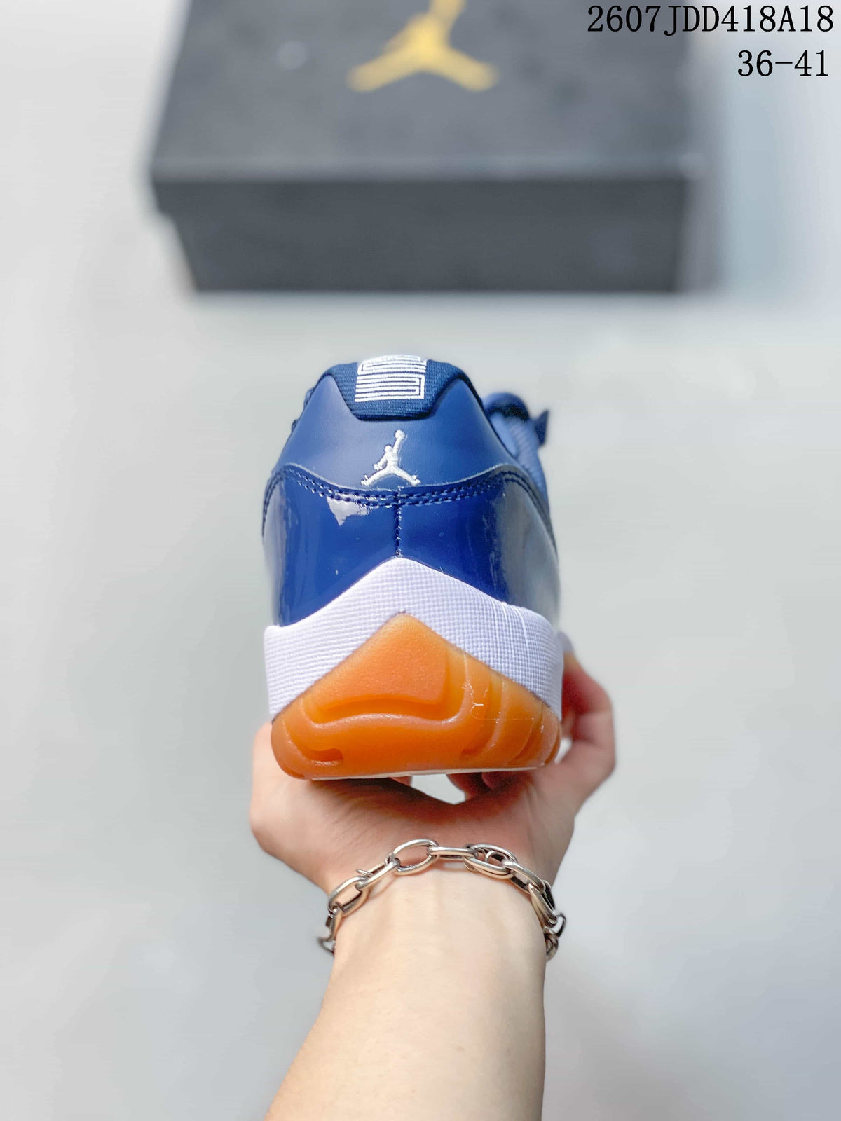 Rear view of the blue high-top sneaker showing the Jordan heel logo, white midsole, and orange outsole.