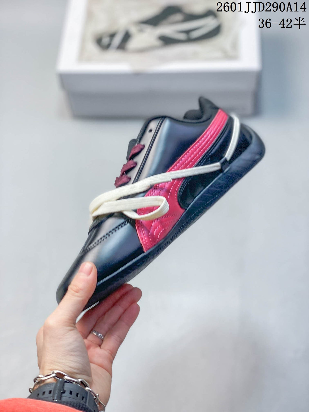 Side profile of the low-profile black sneaker with red side panels, white laces, and a black outsole.