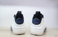 Rear view of white Nike Air Foamposite One high-tops with black collars and blue heel logos