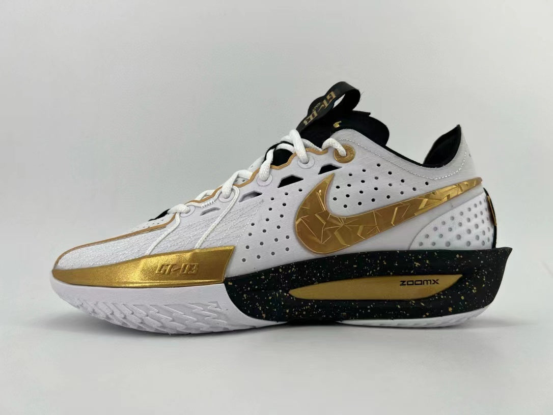 Side view of a white Nike basketball shoe with gold accents, a patterned Swoosh, and a black speckled midsole.