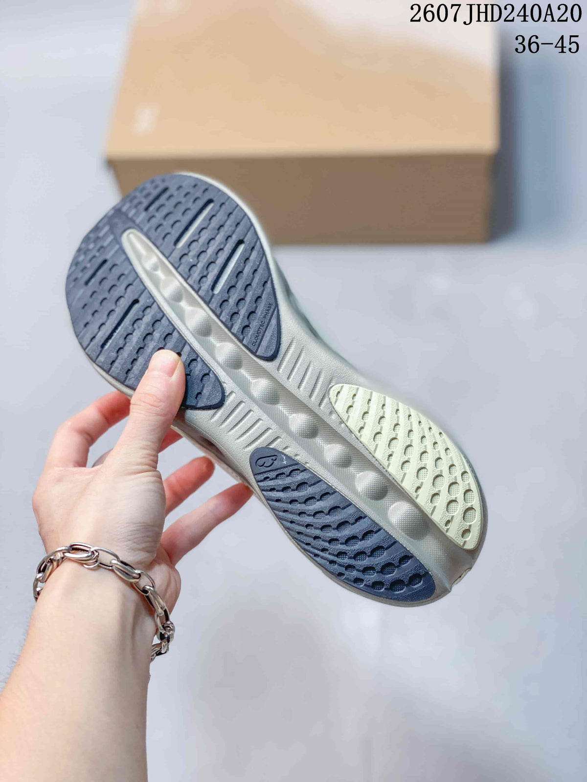 Underside of a white sneaker showing the dark patterned outsole and open cushioning channels.