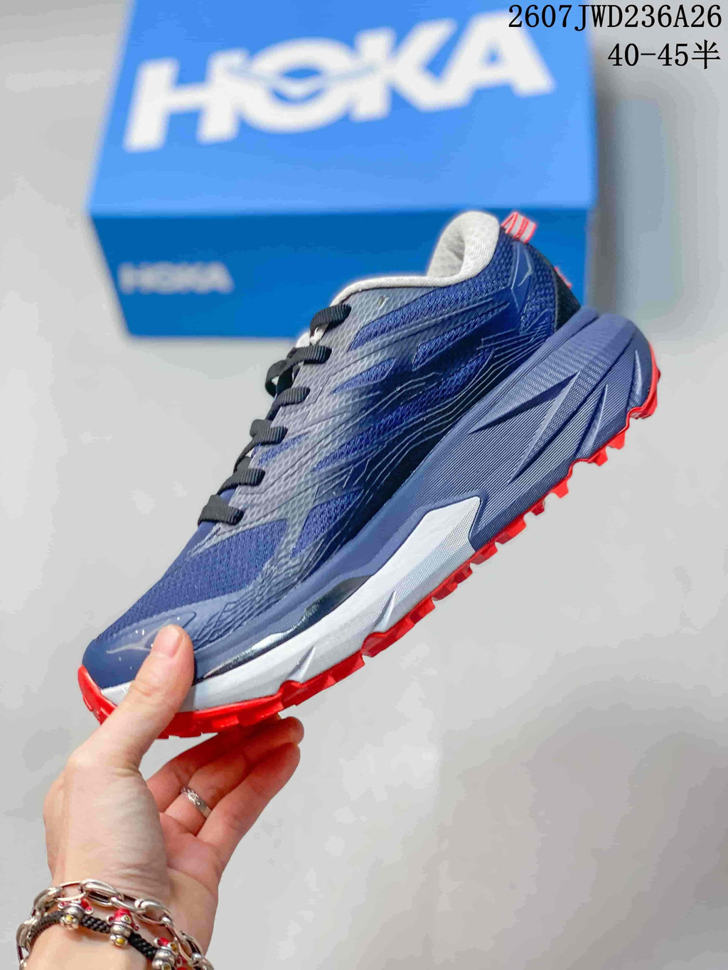 Side view highlighting the layered navy upper, thick midsole, and red outsole lugs.