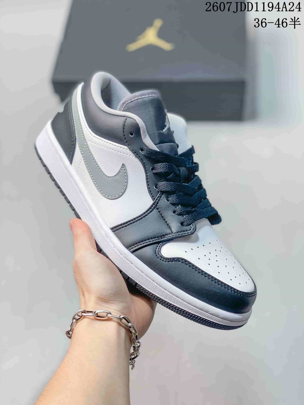 Black-and-white low-top Jordan sneaker shown from a closer front three-quarter angle, highlighting the layered side panels and perforated toe box.