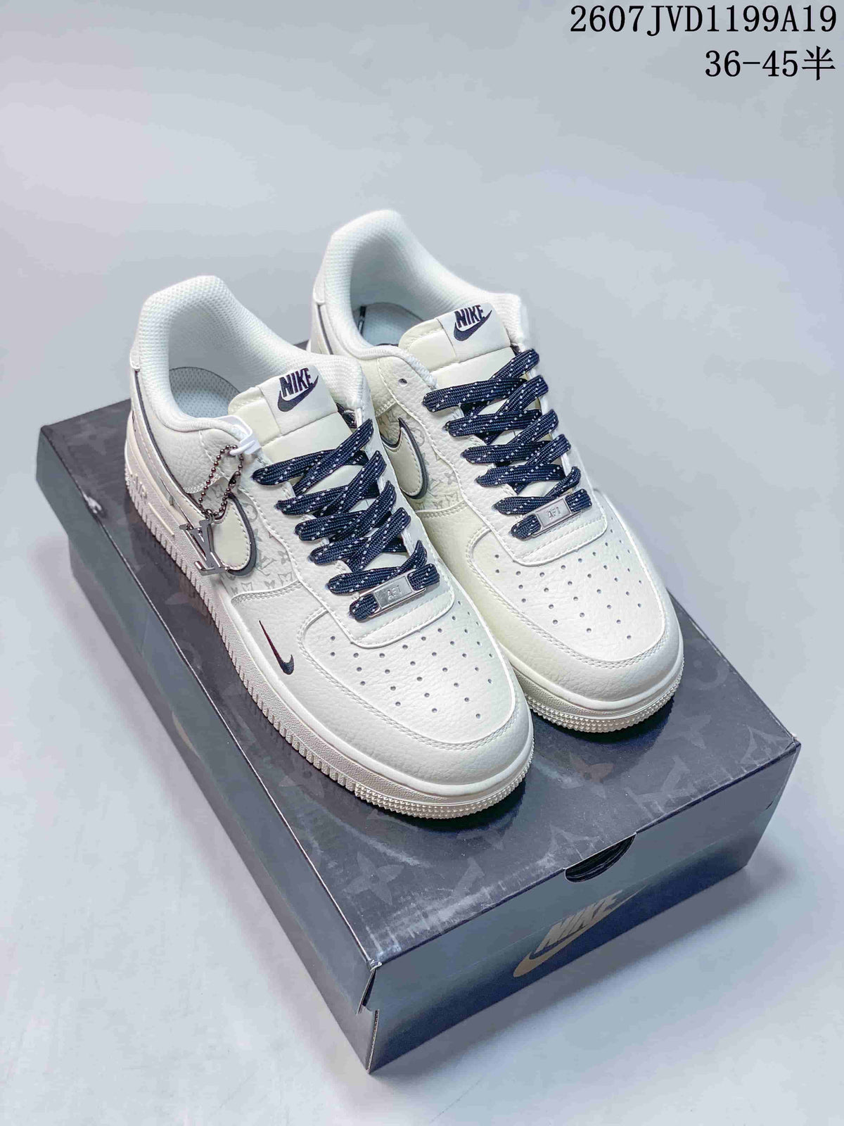 Pair of white Nike Air Force 1 low-top sneakers with dark blue laces displayed on a shoebox; image text shows style code 2607JVD1199A19 and size range 36–45.