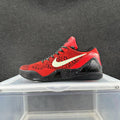 Red and black Nike basketball sneaker displayed in side profile on a clear stand.