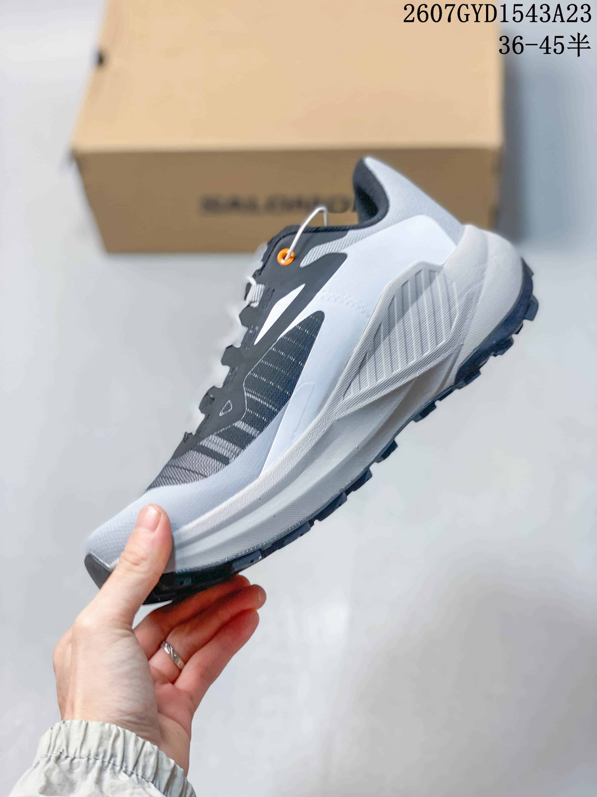 Side profile of the gray and white trail running shoe with dark upper panels and a textured outsole.