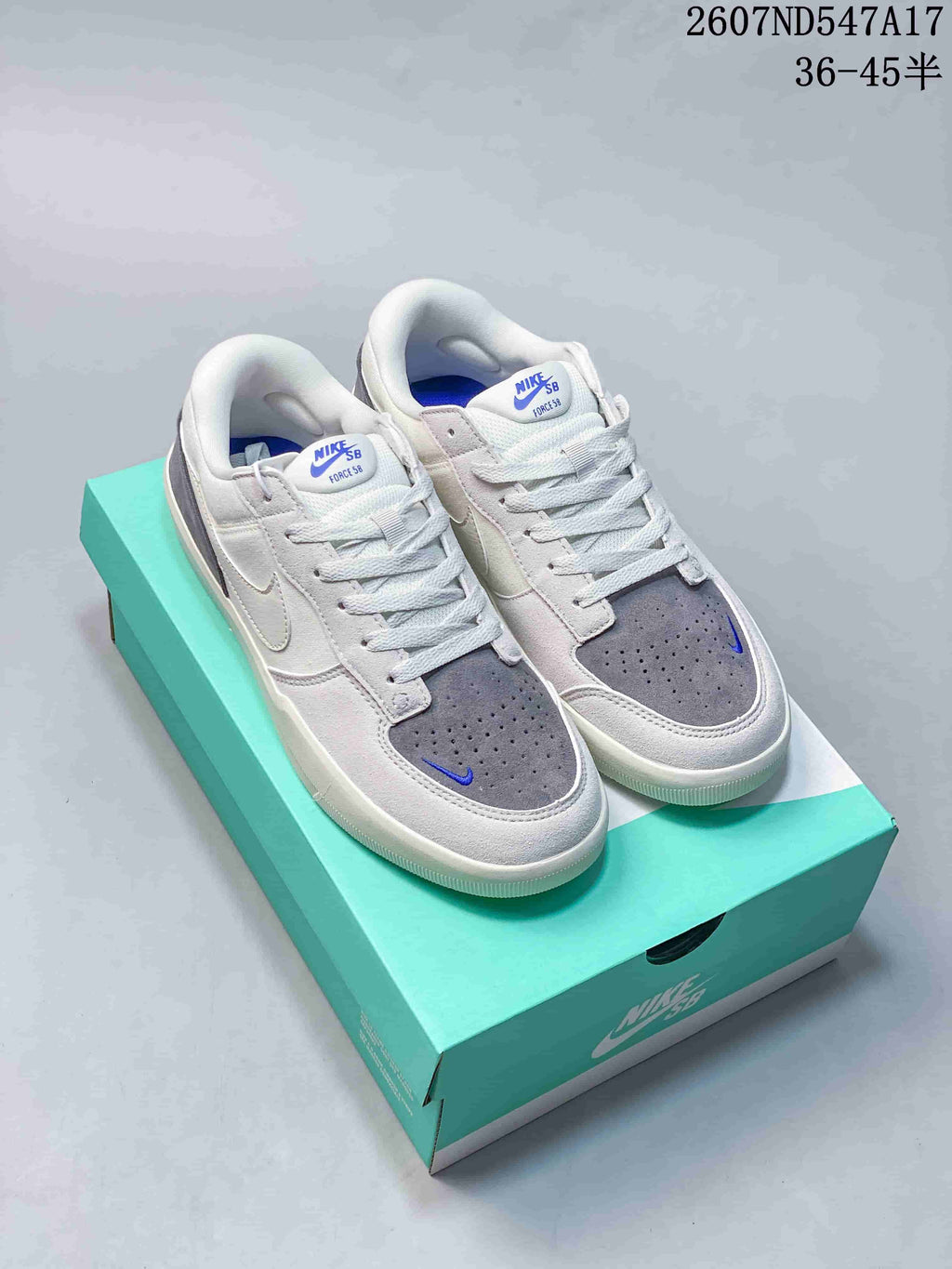 Pair of Nike SB Force 58 sneakers in white, grey and blue displayed on a turquoise shoebox; image text shows style code 2607ND547A17 and size range 36–45.5.