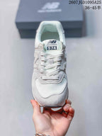 Front view of the white and grey New Balance 574 sneaker showing the laces, tongue branding, and layered toe panels.