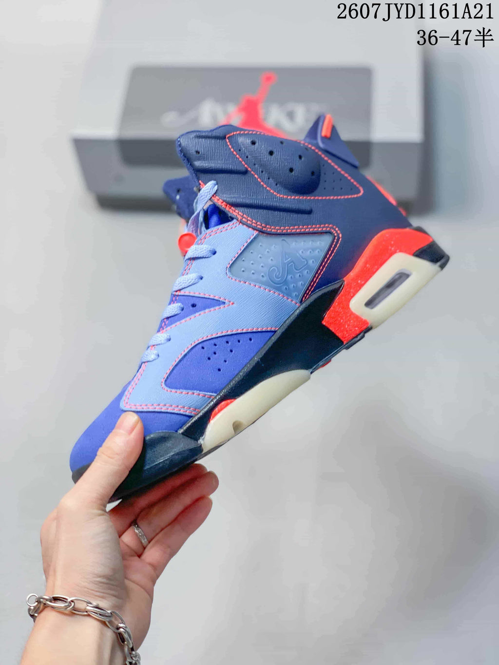 Side profile of a blue high-top sneaker with red stitching, perforated panels, a visible air cushioning window, and a sculpted sole.