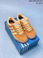 Pair of orange and cream adidas Samba ADV sneakers displayed on a blue shoebox.