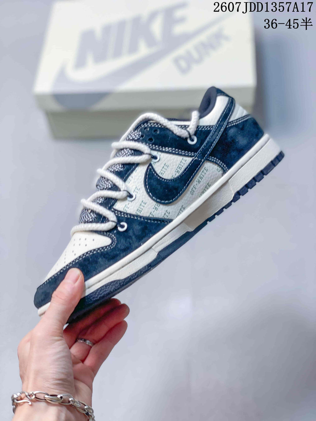 Side profile of the navy and white low-top sneaker showing the layered lacing and contrasting side panels.