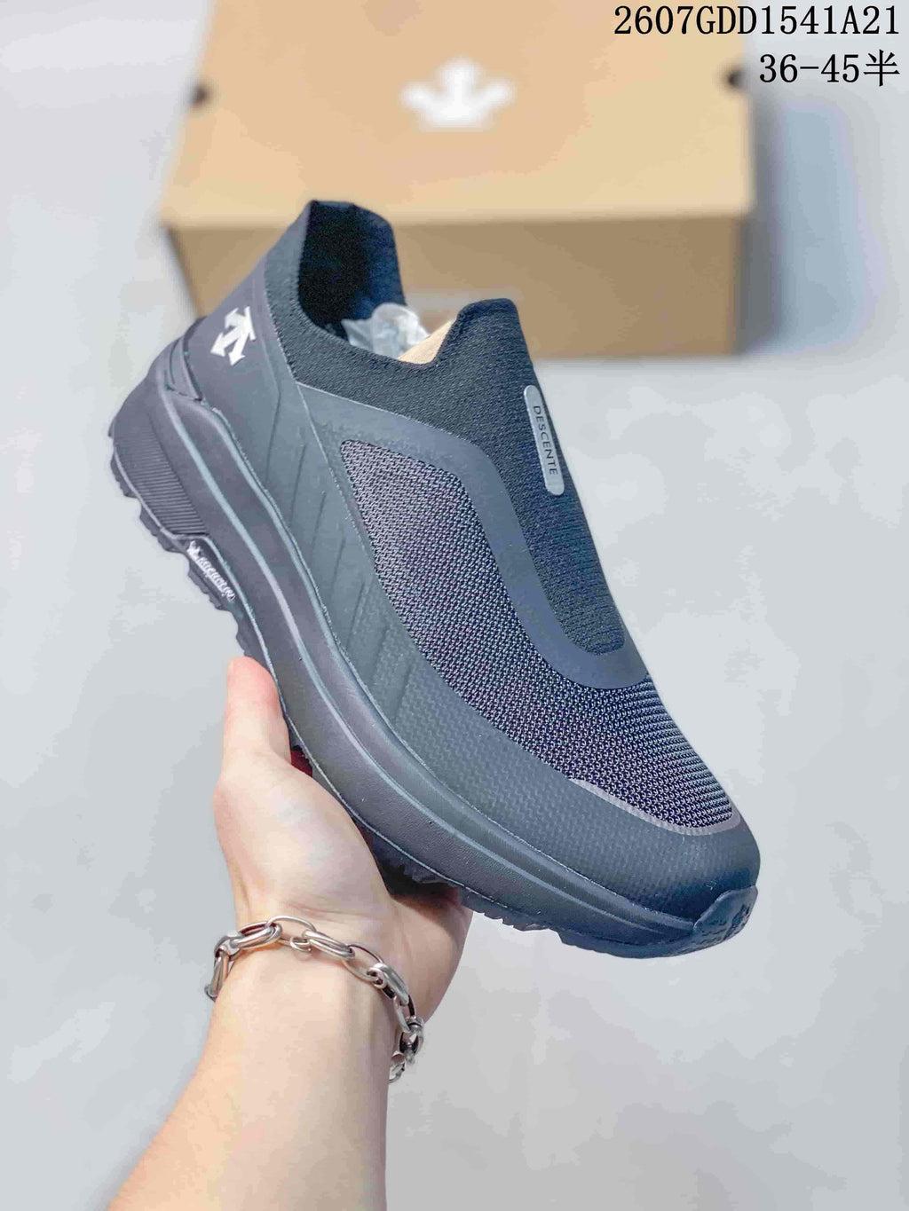 Three-quarter side view of the dark DESCENTE sneaker showing the upper panels, heel branding, and rugged outsole.