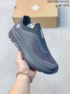 Three-quarter side view of the dark DESCENTE sneaker showing the upper panels, heel branding, and rugged outsole.