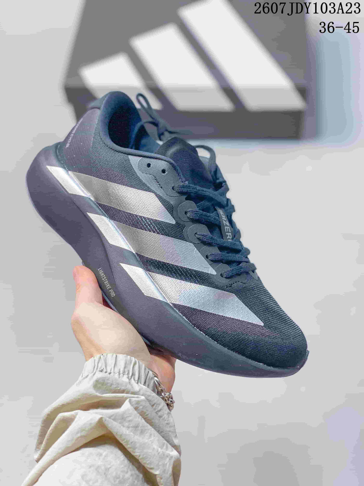 Dark adidas Adizero low-top sneaker with pale side stripes and a visible LIGHTSTRIKE PRO midsole marking.