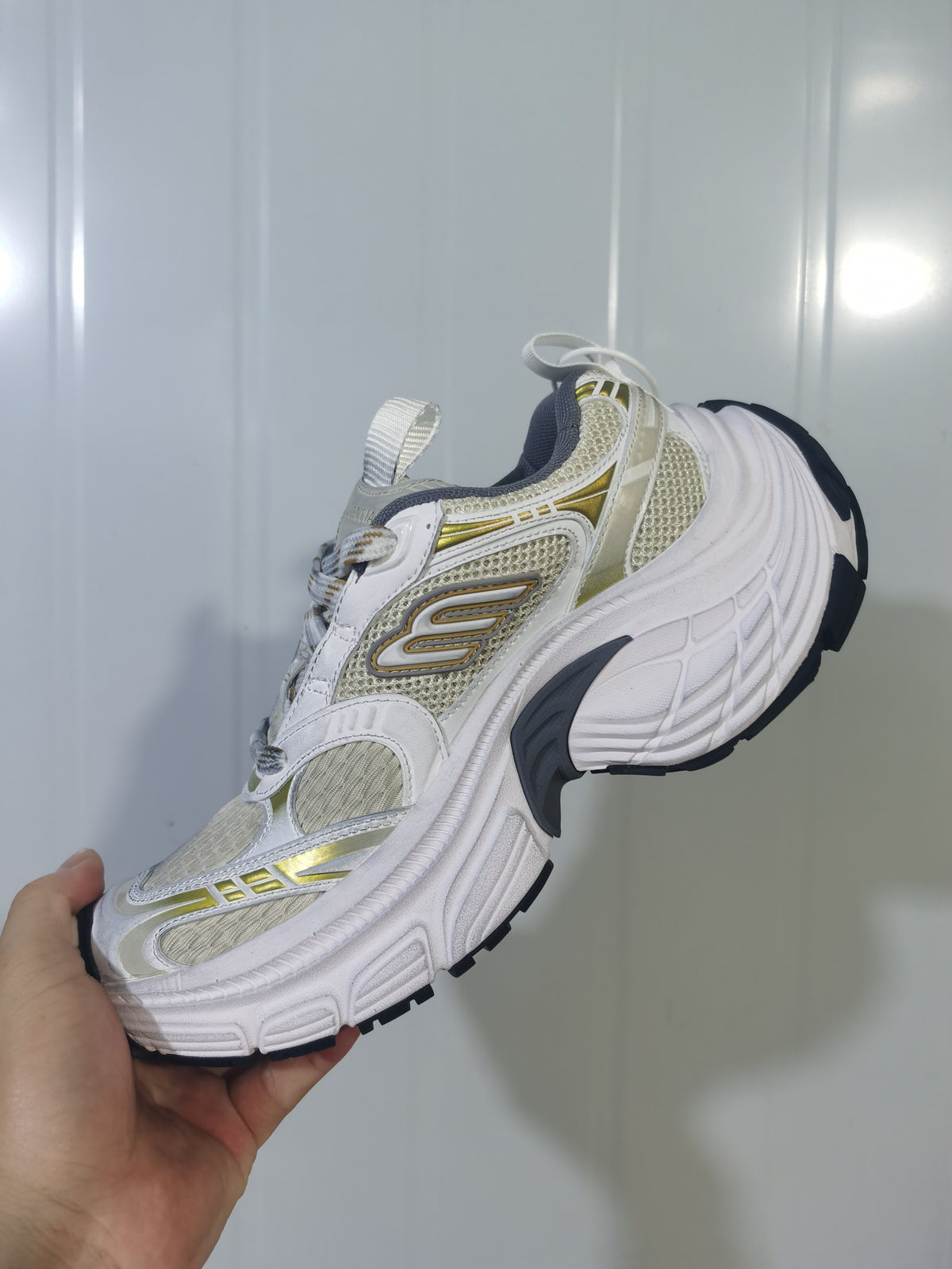 Close angled view of the sneaker's mesh upper, layered side panels, lace area, and black outsole.