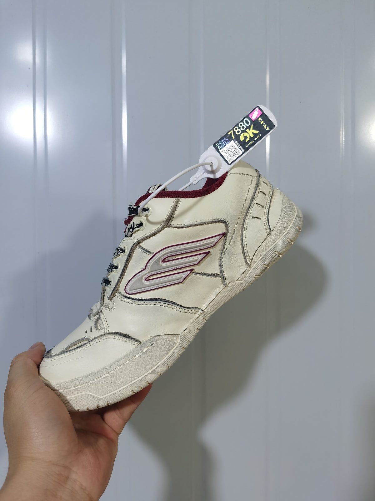 Close angled view of the Balenciaga Hamptons sneaker highlighting the side logo, red collar and textured outsole.