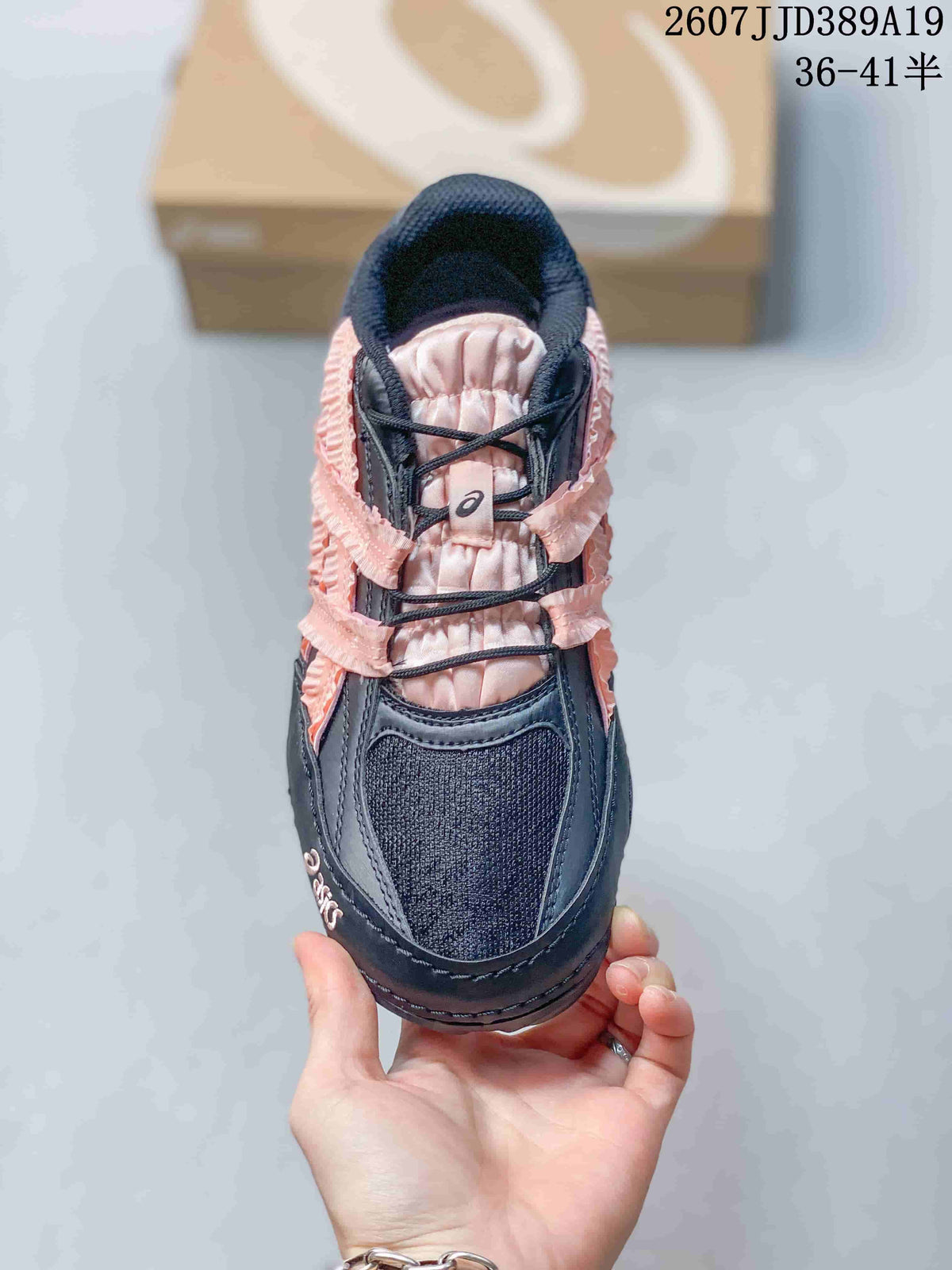 Top view of a black ASICS sneaker showing the textured toe panel, padded tongue, laces, and pink accents.