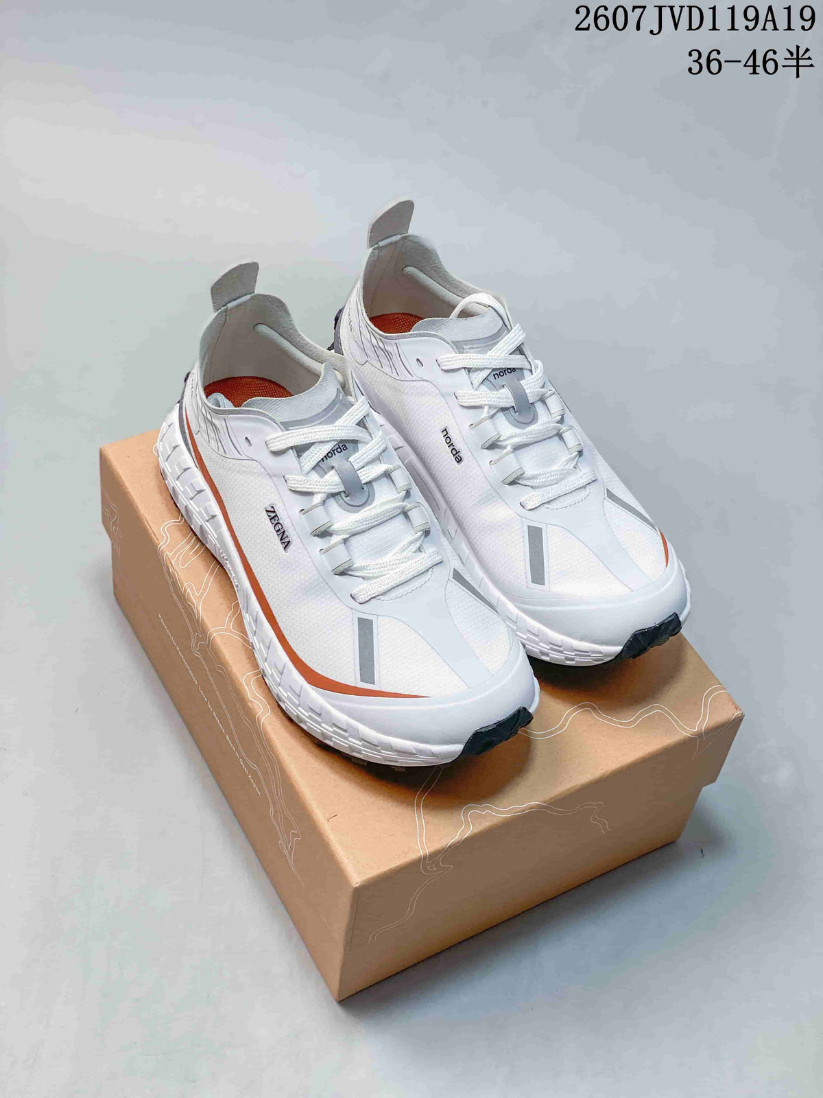 White NORDA sneakers with orange accents displayed on a shoebox, with the style code and size range visible above.