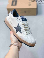 Close-up of a white Golden Goose Ball Star sneaker with a dark navy star, navy collar lining, cream laces, and a textured toe and sole.