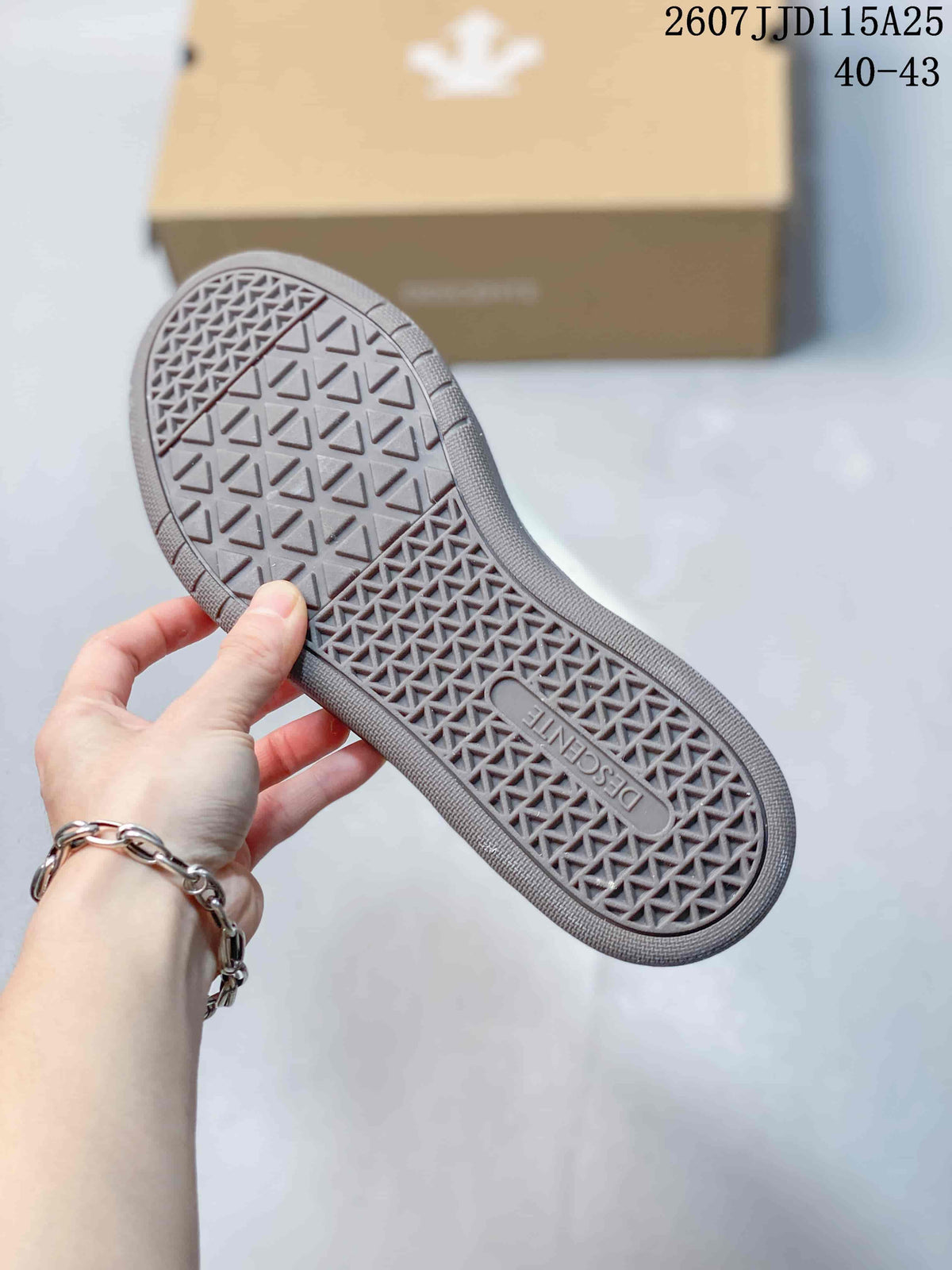 Close view of the gray outsole showing a geometric tread pattern and DESCENTE branding