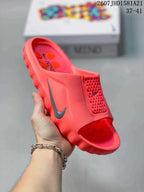 Angled view of the coral Nike Mind 001 mule slide showing the open toe, Nike Swoosh and textured upper panel.