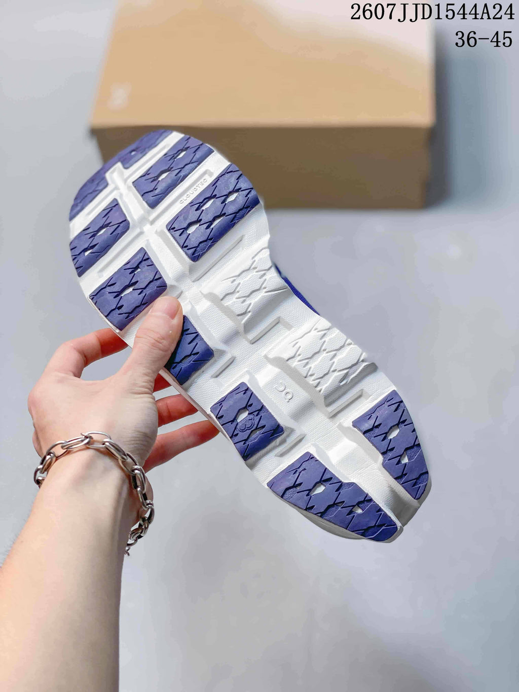 Underside view of the shoe showing the segmented purple-and-white outsole with geometric traction sections.