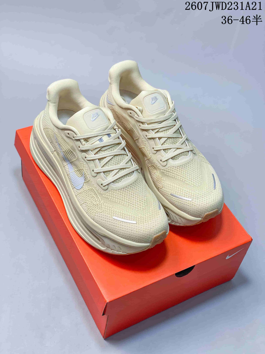 Pair of light cream Nike Air Pegasus Premium sneakers displayed on an orange shoebox.